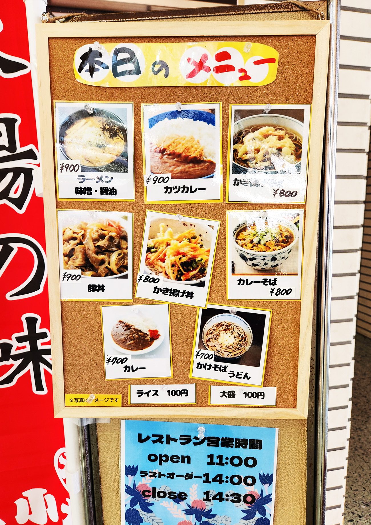 ボードにメニューの写真と価格帯が掲載されている。左上からラーメン味噌・醤油（900円）、カツカレー（900円）、かき揚げそば（800円、豚丼（900円）、かき揚げ丼（800円）、カレーそば（800円）、カレー（700円）、かけそば・うどん（700円）、ライス（100円）。100円追加で大盛にもできるようだ。